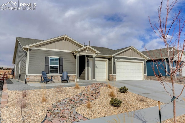 view of front facade featuring an attached garage, stone siding, board and batten siding, and concrete driveway