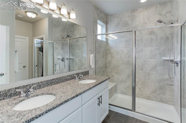 full bath featuring double vanity, a stall shower, a sink, and tile patterned floors