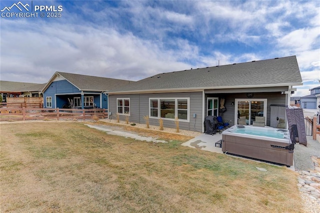 rear view of property featuring a patio area, fence, a hot tub, and a lawn