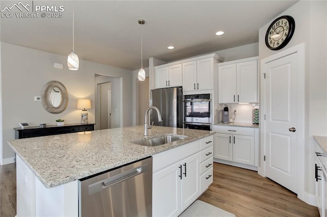 kitchen featuring light wood-style flooring, a kitchen island with sink, stainless steel appliances, white cabinetry, and a sink