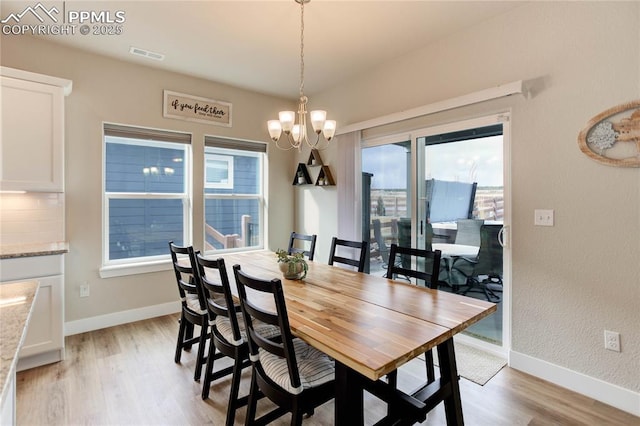 dining space featuring light wood-style floors, baseboards, visible vents, and an inviting chandelier