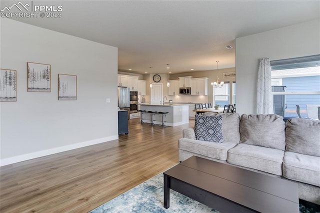 living room with recessed lighting, visible vents, baseboards, light wood-type flooring, and an inviting chandelier