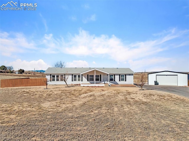 ranch-style home featuring a detached garage, fence, and an outbuilding