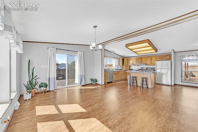 kitchen with open floor plan, appliances with stainless steel finishes, brown cabinets, and ornamental molding