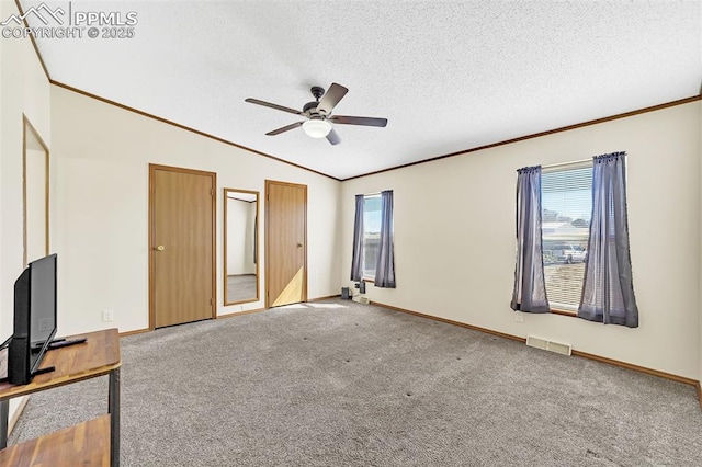 unfurnished bedroom featuring visible vents, ornamental molding, carpet flooring, vaulted ceiling, and a textured ceiling