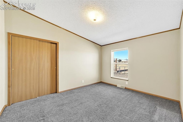 unfurnished bedroom with crown molding, visible vents, carpet flooring, vaulted ceiling, and a textured ceiling