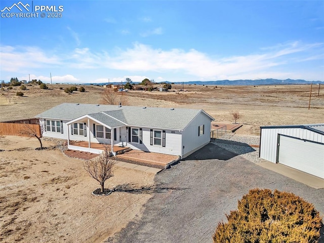 ranch-style home with an outbuilding, a patio area, fence, a mountain view, and driveway