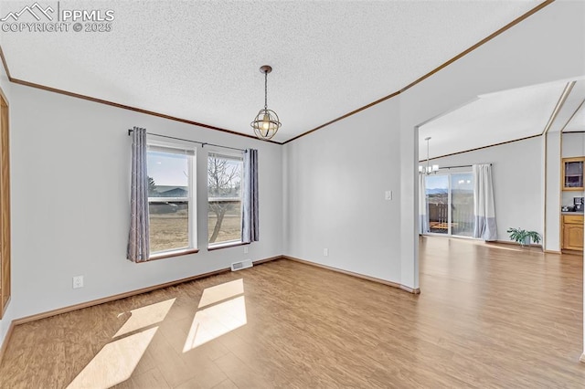 spare room featuring visible vents, a textured ceiling, a chandelier, and wood finished floors