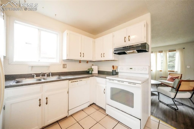 kitchen with under cabinet range hood, white appliances, white cabinetry, and a sink