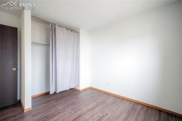 unfurnished bedroom with a closet, baseboards, and wood finished floors