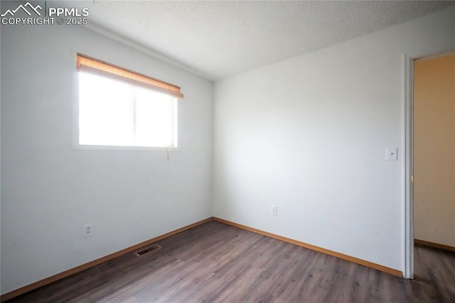 empty room with visible vents, baseboards, a textured ceiling, and wood finished floors