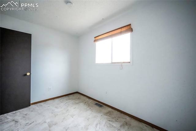 empty room featuring visible vents, a textured ceiling, and baseboards