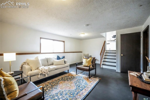 living area with concrete floors, a textured ceiling, and stairs