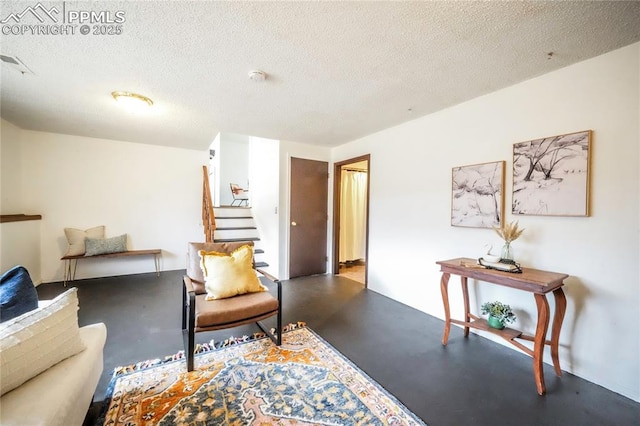 living area with visible vents, a textured ceiling, finished concrete floors, and stairs