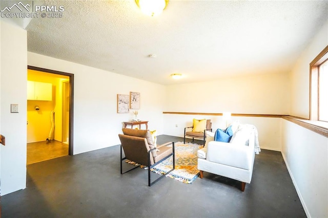 living area featuring baseboards, concrete flooring, and a textured ceiling