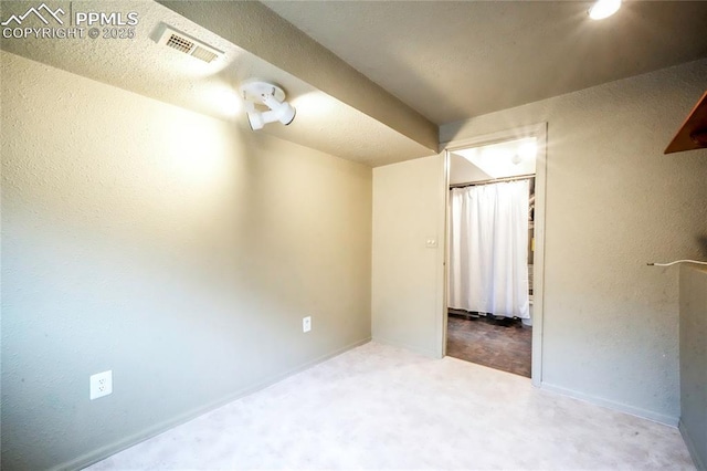 interior space featuring visible vents, a textured ceiling, baseboards, and a textured wall