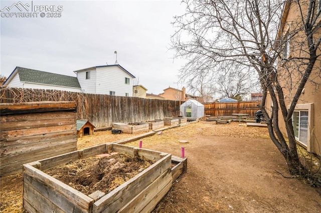 view of yard featuring an outbuilding, a fenced backyard, and a vegetable garden