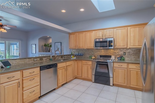 kitchen featuring appliances with stainless steel finishes, tasteful backsplash, a sink, and light brown cabinetry