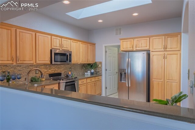 kitchen with stainless steel appliances, a skylight, visible vents, backsplash, and light brown cabinetry