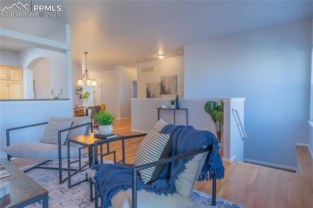 interior space featuring a chandelier, light wood-type flooring, visible vents, and baseboards