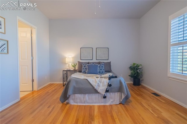 bedroom with light wood-style floors, visible vents, and baseboards