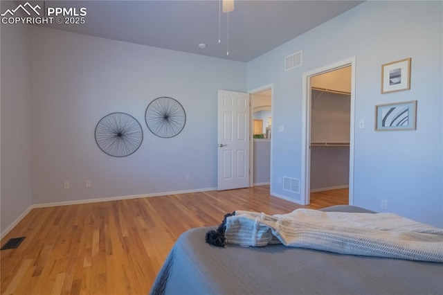 bedroom featuring visible vents, a spacious closet, and wood finished floors