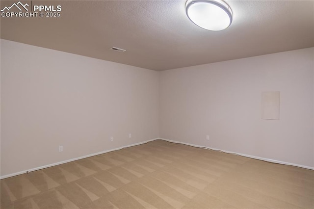 spare room with light carpet, visible vents, and a textured ceiling