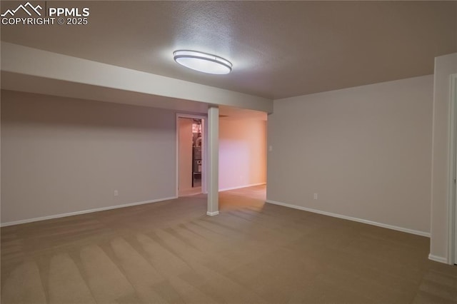 finished below grade area featuring a textured ceiling, carpet flooring, and baseboards