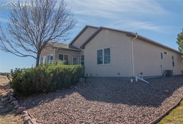 view of side of property with central air condition unit and stucco siding