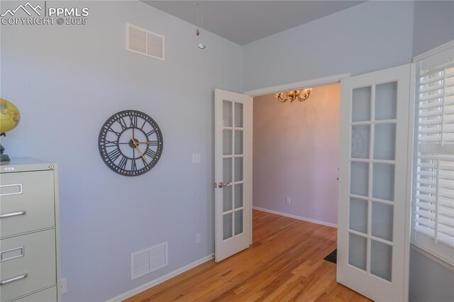 unfurnished room with light wood-style floors, baseboards, visible vents, and french doors