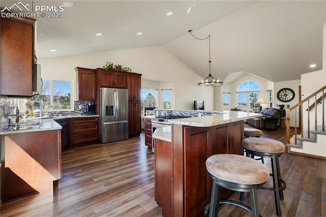 kitchen with a center island, dark wood-style flooring, stainless steel appliances, lofted ceiling, and decorative backsplash