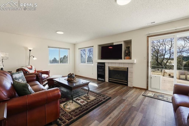 living room featuring a textured ceiling, wood finished floors, and a tile fireplace