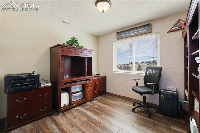 office space with a textured ceiling, wood finished floors, visible vents, and baseboards