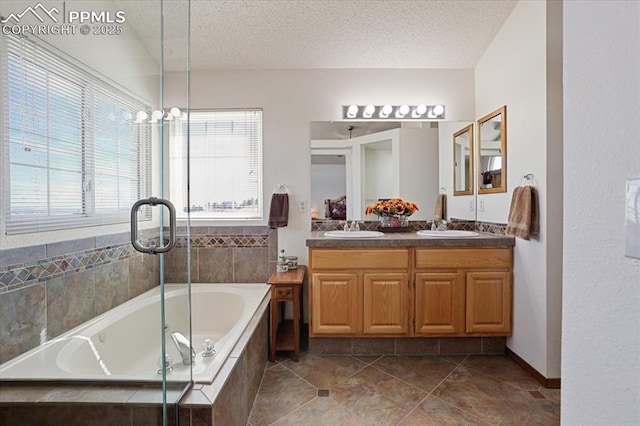 bathroom featuring a textured ceiling, double vanity, a sink, and a garden tub