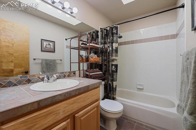 bathroom featuring a skylight, toilet, tile patterned flooring, shower / bath combination with curtain, and vanity