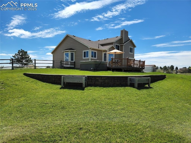 rear view of property with a lawn, a deck, and fence