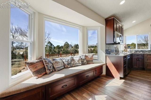 interior space featuring lofted ceiling, wood finished floors, a textured ceiling, a sink, and recessed lighting