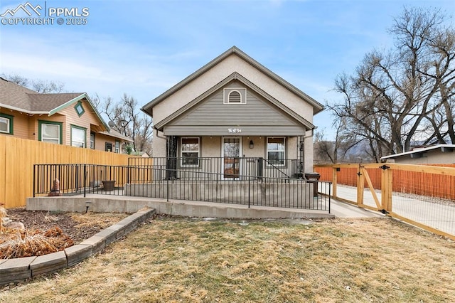 view of front of property with covered porch, fence, a gate, and stucco siding