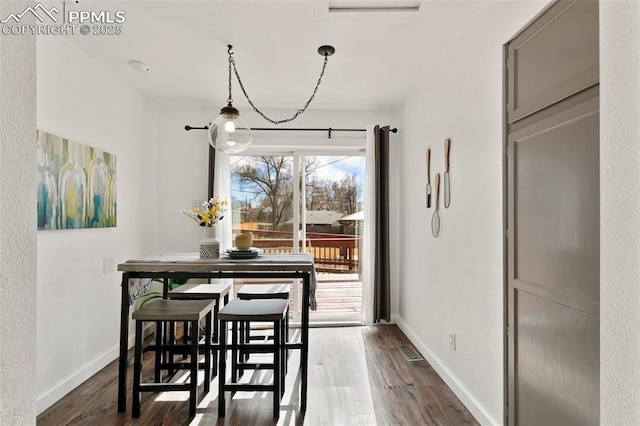 dining area with baseboards and dark wood-type flooring