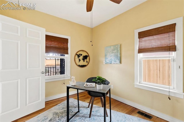 home office featuring a ceiling fan, baseboards, visible vents, and wood finished floors