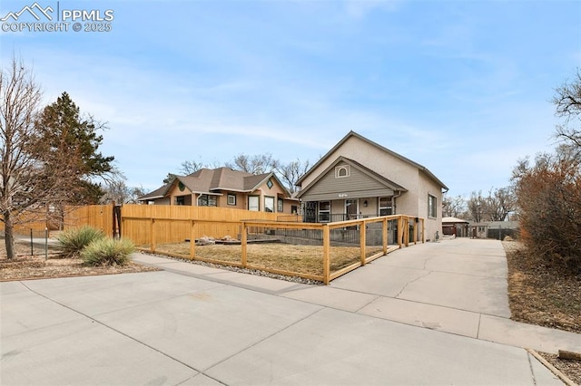 view of front of property featuring concrete driveway, a fenced front yard, and a gate