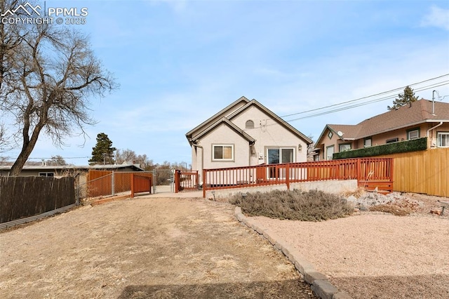 back of property featuring fence private yard, a gate, driveway, and a wooden deck