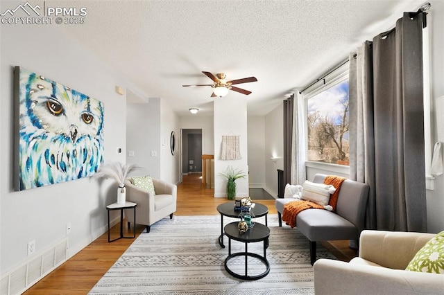 sitting room featuring baseboards, visible vents, ceiling fan, wood finished floors, and a textured ceiling