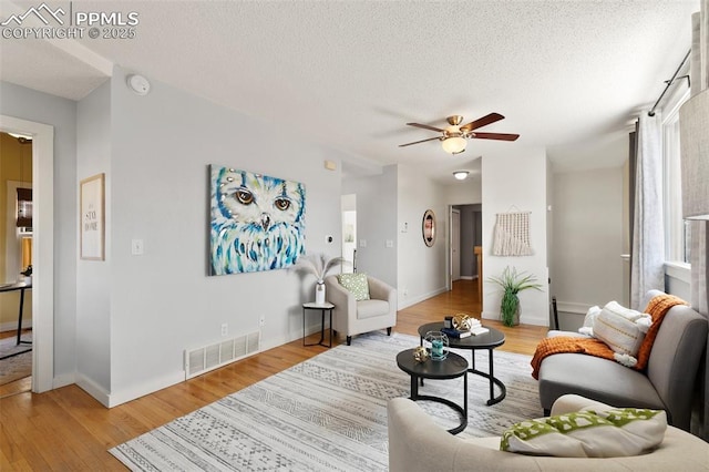 living room featuring visible vents, ceiling fan, a textured ceiling, and wood finished floors