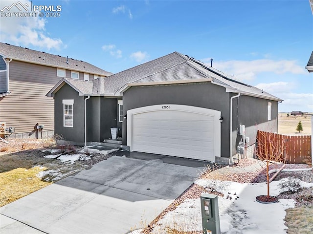 traditional-style home with stucco siding, driveway, an attached garage, and fence