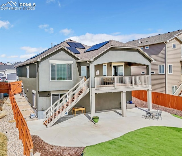 back of house with solar panels, a patio, a fenced backyard, and stucco siding