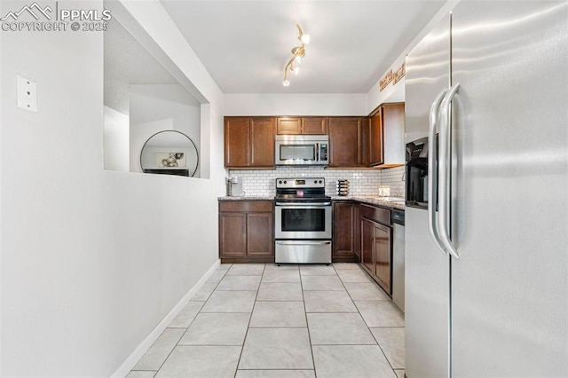 kitchen with baseboards, tasteful backsplash, appliances with stainless steel finishes, and light tile patterned flooring