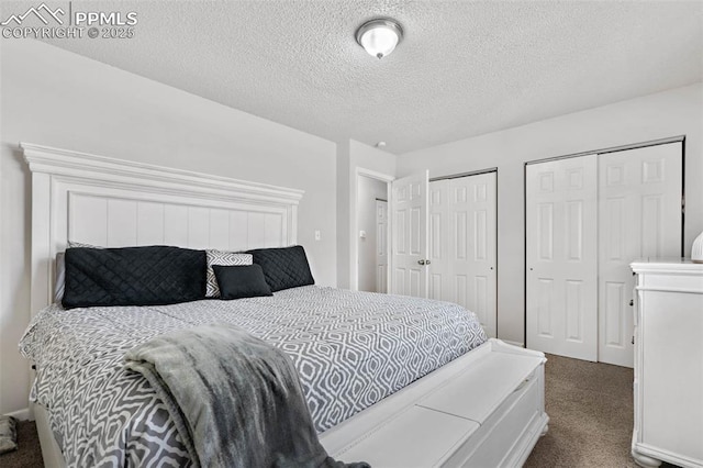 carpeted bedroom featuring two closets and a textured ceiling