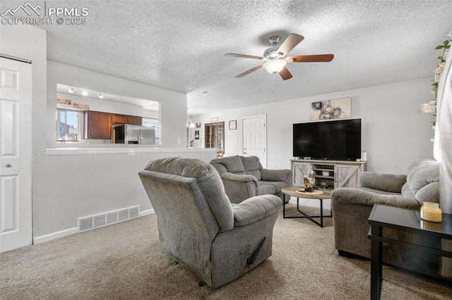 living area with a ceiling fan, baseboards, visible vents, a textured ceiling, and light carpet