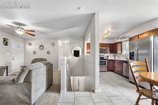 living room featuring light tile patterned floors, baseboards, a textured ceiling, and a ceiling fan